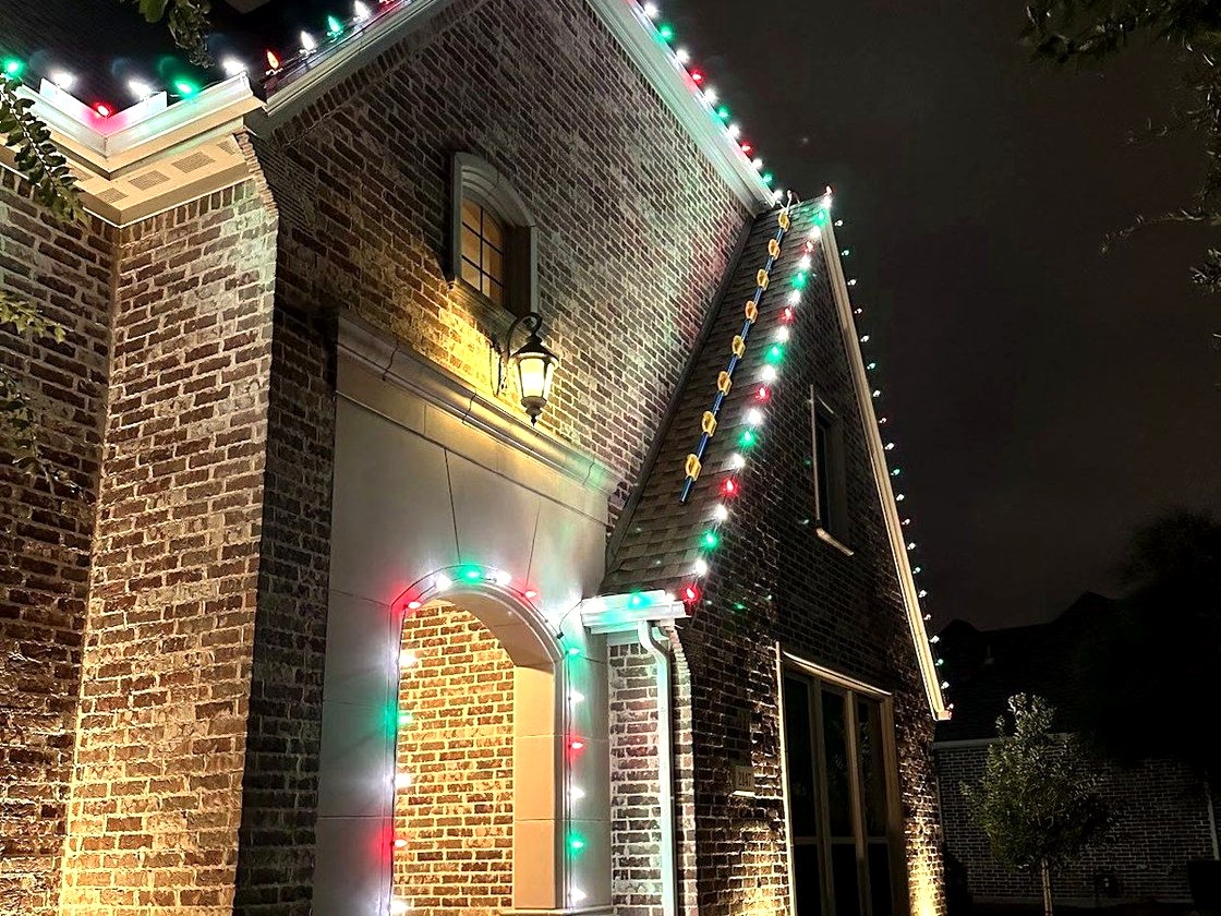 Brick home with red, green, and white lights around the entry