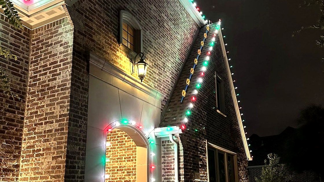 Brick home with red, green, and white lights around the entry