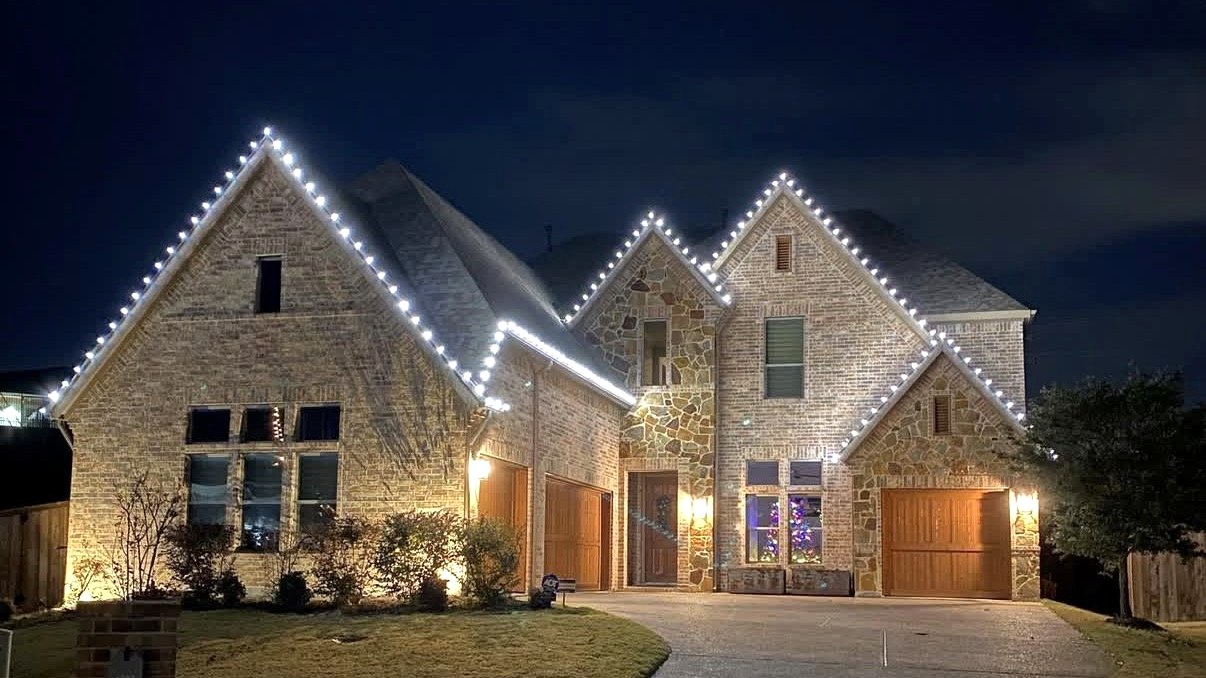 Two-story stone home with white roofline lighting
