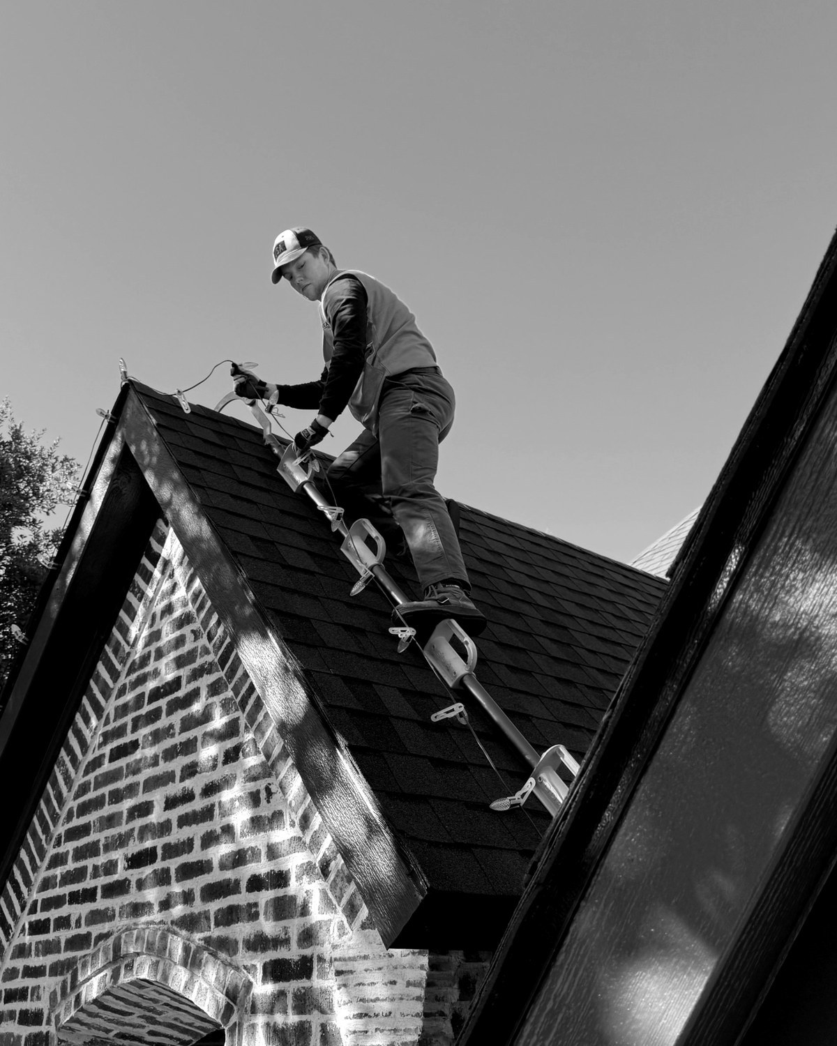 A Bright's crew member clipping lights along a roof peak